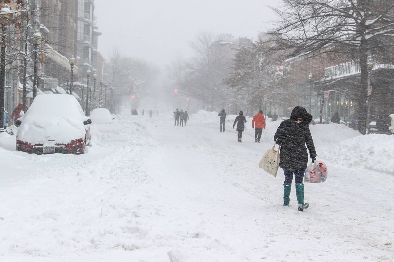 people walking on the street as it snows