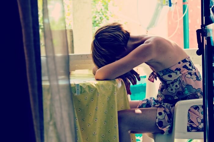 distressed woman sitting at table covering her face