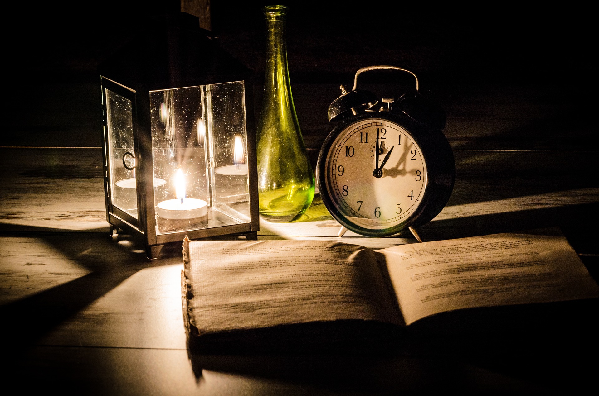 At the top of a desk is a lamp, clock,book and vase
